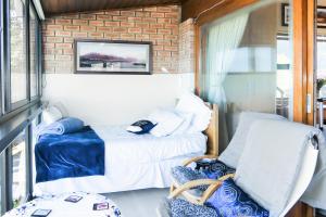 ein Schlafzimmer mit einem Bett und einem Stuhl in einem Zimmer in der Unterkunft Shalom Self Catering in Kleinmond