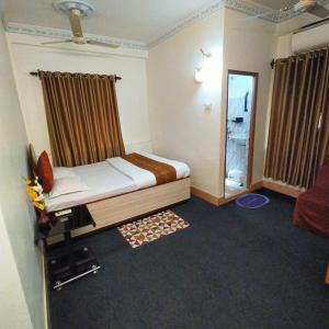 Tulip 1bhk Apartment by Hotel Airways في كولْكاتا: غرفة نوم صغيرة مع سرير ومرآة