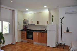 una cucina con armadietti bianchi e frigorifero bianco di Acogedor apartamento en entorno rural a Massanas