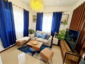 a living room with a couch and a tv and blue curtains at Elon's Place in Catarman