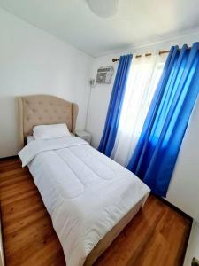 a bedroom with a bed and blue curtains at Elon's Place in Catarman