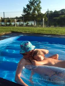 a man and a child in a swimming pool at Lux apartments in Orosháza