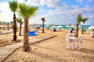 una playa con palmeras, mesa y sillas en Paradise Inn Beach Resort, en Alejandría
