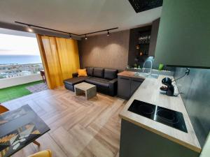 a kitchen and a living room with a couch at Stonefall Tenerife Holiday Apartment Las Americas in Playa Fañabe