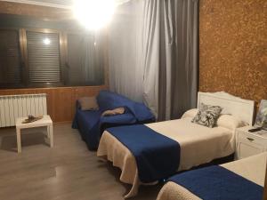 ein Zimmer mit 2 Betten und einem Stuhl darin in der Unterkunft El Camino in Laza