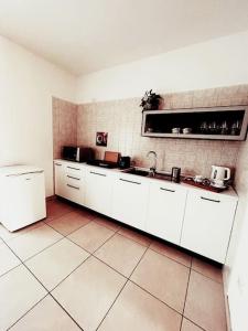a kitchen with white cabinets and a tile wall at Sunny House Fourteen in Assemini