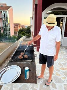 a man is cooking hamburgers on a grill at Villa Hercegovina in Sveti Filip i Jakov