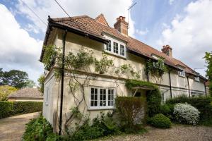 an old house with ivy on the side of it at Spacious family cottage with private garden and forest walks in Burley