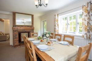a dining room with a table and a fireplace at Spacious family cottage with private garden and forest walks in Burley
