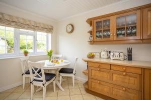 a kitchen with a table and a table and chairs at Spacious family cottage with private garden and forest walks in Burley