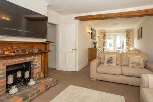 a living room with a couch and a fireplace at Spacious family cottage with private garden and forest walks in Burley