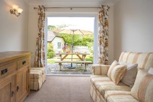 a living room with a couch and a table with an umbrella at Spacious family cottage with private garden and forest walks in Burley