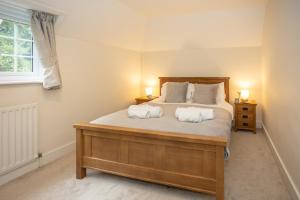 a bedroom with a large bed with two white pillows at Spacious family cottage with private garden and forest walks in Burley