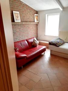 a red leather couch in a room with a brick wall at Apartment in Nijmegen voor 3 personen in Kranenburg