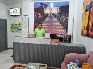 un hombre parado detrás de un mostrador en una habitación en Grand Hotel &Hostel, en Luxor