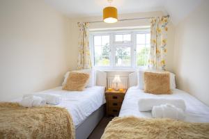 two twin beds in a room with a window at Spacious family cottage with private garden and forest walks in Burley +19 photos