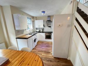 a kitchen with white cabinets and a wooden table at Penny Cottage By The Beach in Portsmouth
