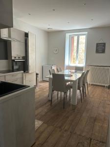 a kitchen and dining room with a table and chairs at Les Ramandes Appartements au cœur du village in Marcillac-la-Croisille