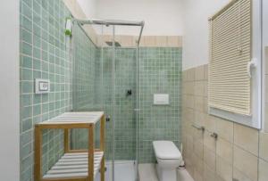 a green tiled bathroom with a shower and a toilet at Casa Cattedrale in Iglesias