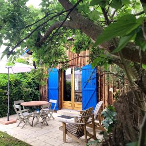 un patio con mesa y sillas y una puerta azul en Gîte le Chai en Le Teich