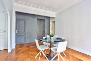 een eetkamer met een tafel en witte stoelen bij Appartement Quartier Parc Monceau in Parijs