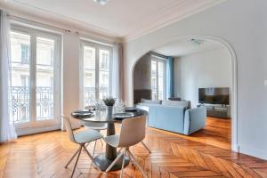 een woonkamer met een tafel en stoelen en een bank bij Appartement Quartier Parc Monceau in Parijs