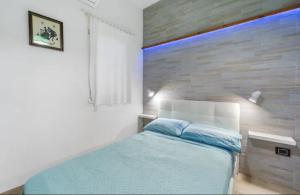 a bedroom with a blue bed and a brick wall at Casa Cattedrale in Iglesias