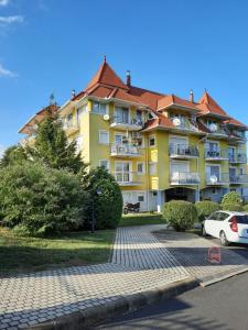 a yellow apartment building with cars parked in front of it at Heviz Victoria apartman in Hévíz