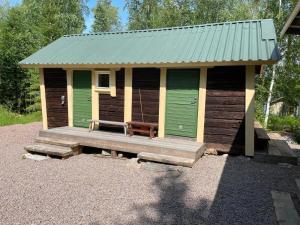 uma pequena cabana com uma porta verde e um alpendre em Koivuisenranta em Kalmari