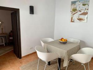 - une table avec des chaises et une corbeille de fruits dans l'établissement Townhouse in Canillas de Aceituno, à Canillas de Aceituno