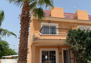 a house with a palm tree in front of it at King`s Apartaments in San Javier