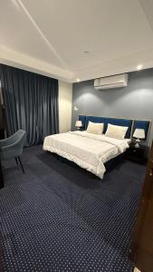 منازل الشمال للشقق المخدومة Manazel Al Shamal Serviced Apartments في حائل: غرفة نوم بسرير كبير وكرسي