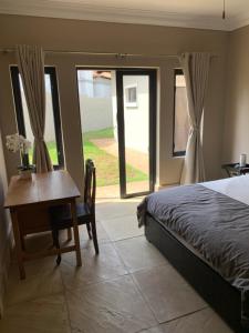 a bedroom with a bed and a desk and a window at Apartment @ Silver Lakes in Pretoria