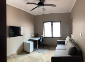 a living room with a couch and a desk and a ceiling fan at Apartment @ Silver Lakes in Pretoria