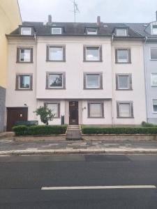 una casa bianca sul lato di una strada di Studio Apartment mit Balkon 13-2L1 a Essen