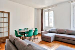 a living room with a couch and a table with green chairs at Appartement Quartier Champs-Élysées in Paris