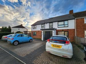 two cars parked in a parking lot in front of a house at Horizon House, Modern 2-Bedroom Flat 2, Parking, Netflix, Oxford in Oxford