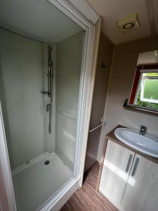ein Bad mit einer Dusche und einem Waschbecken in der Unterkunft Mobil Home Cosi pour 6 (Camping Tohapi) in Vogelgrun