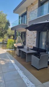 eine Terrasse mit einem Tisch, Stühlen und einem Sonnenschirm in der Unterkunft Danielli Luxury Villas in Skala Rachoniou