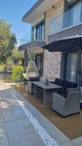 a patio with a table and chairs and an umbrella at Danielli Luxury Villas in Skala Rachoniou