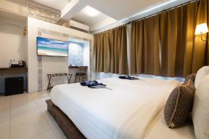 a bedroom with a large white bed and a window at Montree Phuket Hotel in Phuket Town