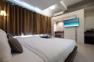 a bedroom with a large white bed and a flat screen tv at Montree Phuket Hotel in Phuket Town