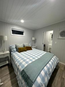 a bedroom with a large bed with a blue and white checked blanket at BENROSE FARM COTTAGES in Wellington