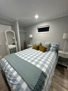 a bedroom with a blue and white bed and two mirrors at BENROSE FARM COTTAGES in Wellington