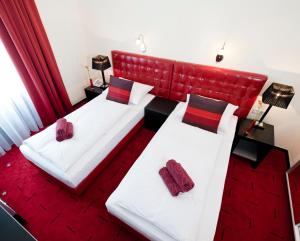 ケルンにあるホテル エスプラナーデの赤をアクセントにしたホテルルーム内のベッド2台