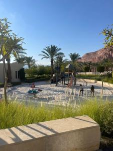 un parco giochi con bambini che giocano in un parco con palme di aladnan Chalet alraha village ad Aqaba