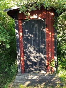 a red shed with a black door in the grass at Semesterhus i Stockholms skärgård, Runmarö. in Nämdö