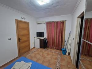 a room with a bed and a television and a door at Habitaciones Miramar in Bolonia