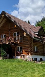 a log house with a balcony and a yard at Chalet le Dorf in Nötsch