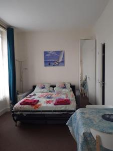 Cabourg Charmant studio centre ville RUE DE LA MER في كابورغ: غرفة نوم بسرير مع لوحة على الحائط